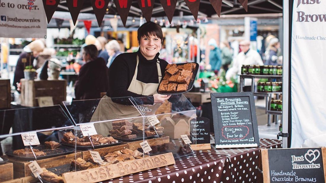 Just Brownies holding up a tray of brownies at her stall